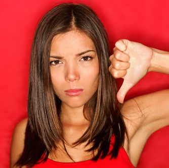 Unhappy woman giving thumbs down gesture looking with negative expression and disapproval. Beautiful cute young mixed race Caucasian / Asian woman on red background.